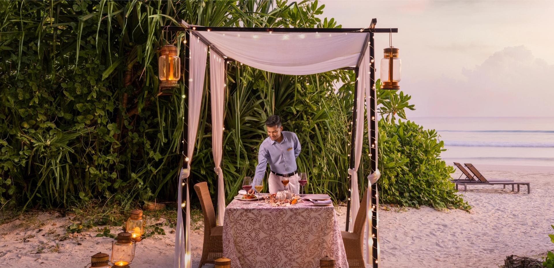 Table dressée au coucher du soleil sur la plage du Taj Exotica Resort & Spa, Radhanagar